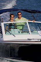 Couple cruising aboard Harrier 25 powerboat off Marco Island, Florida, USA. Model and property released, 2007.