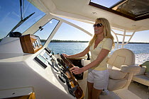 Woman helming Surf Hunter 33 Jet boat off Marco Island, Florida. Model and property released, 2007.