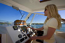 Woman helming Surf Hunter 33 Jet boat off Marco Island, Florida. Model and property released, 2007.