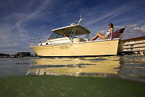 Woman relaxing on the stern of a Surf Hunter 29 Inboard off Marco Island, Florida, USA. Model and property released, 2007.