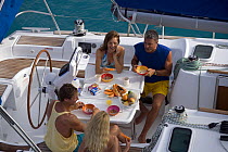 Friends eating breakfast in cockpit of Sunsail Oceanis 423, British Virgin Islands. Model released and property released, March 2006.