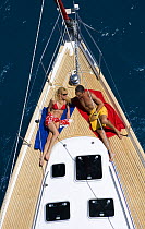 Couple relaxing on bow of yacht in the British Virgin Islands, Caribbean. Model released, March 2006.