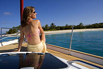 Woman relaxing on the bow of a Sunsail yacht in the British Virgin Islands, Caribbean. Model and Property released, March 2006.