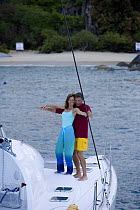 Couple doing exercises on the bow of a cruising Sunsail Lagoon 410 catamaran, British Virgin Islands. Model Released, April 2006.