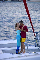 Couple dancing on foredeck of a cruising Sunsail Lagoon 410 catamaran, British Virgin Islands. Model Released, April 2006.