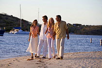 Two couples walking along Bitter End beach at sunset, British Virgin Islands, April 2006. Model Released.