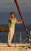 Woman on bow of Sunsail Lagoon 410 catamaran at sunrise, British Virgin Islands, April 2006. Model released and property released.