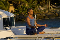 Man doing yoga pose on foredeck of Sunsail Lagoon 410 catamaran, British Virgin Islands, April 2006. Model released.