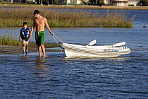 Father and son pulling a tender through the shallows, St. Augustine, Florida, USA. Model Released.