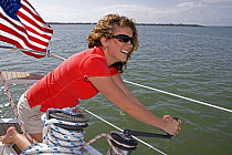 Young woman winching aboard a Hunter 49 yacht off St. Augustine, Florida, USA. Model and Property released, 2006.