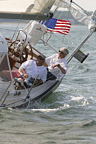 Two men sitting in the cockpit on the leeward side of a Shannon 39 yacht near East Hampton, New York. June 2005.  Model and property released.