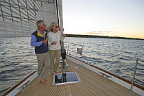 Couple drinking champagne on foredeck of 80ft. Oyster "Darling", Narragansett Bay, Newport, Rhode Island, September 2005. Model and property released.
