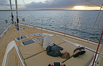 Woman watching sunset from foredeck of 80ft. Oyster "Darling". Narragansett Bay, Newport, Rhode Island, September 2005. Property released.