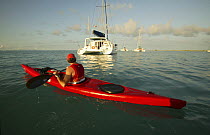Man kayaking past catamaran "Pitch Pin" anchored in the British Virgin Islands, January 2004.  Model and property released.