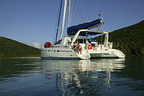Couple relaxing on stern of Moorings Charter catamaran "Pitch Pin" anchored in the British Virgin Islands, January 2004. Model and property released.