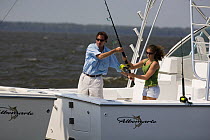 Couple with fishing rod on aftdeck of a sportsfisher.  Model and property released.