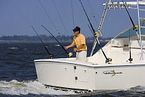 Man fishing from the stern of a sportsfisher.  Model and property released.