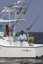 People fishing from the stern of a sportsfisher.  Model and property released.