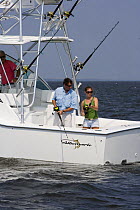 People fishing from the stern of a sportsfisher.  Model and property released.