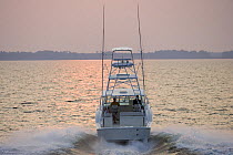 Sportsfisher boat underway at sunset.