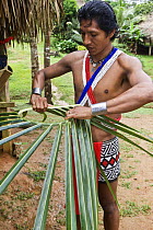 Young Embera Indian man wearing a traditional beaded skirt, creating handicrafts, Panama, November 2008