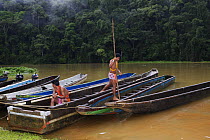 Young Embera Indian men dressed in traditional beaded skirts tending to the village boats, Charges River, Panama, November 2008