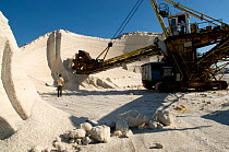 Stocks of salt and conveyor machinery at commerical salt farm, Salin de Giraud, Camargue, France, July 2008