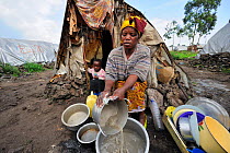 Woman washing dishes in front of her tent at the refugee camp Mugunga 1, west of Goma, North Kivu, Democratic Republic of Congo, Africa, March 2009
