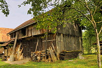 Wooden barn with stored hay and stacked firewood, Croatia.