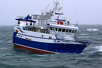 Fishing vessel "Harvester" hauling trawl net onboard, near a North Sea oil platform. June 2009. Property Released.