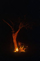 Travellers beside campfire at night, Savuti, Chobe National Park, Botswana, October