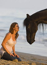 Purebred black Friesian gelding with owner at Summerland Beach, Ojai, California, USA Model released