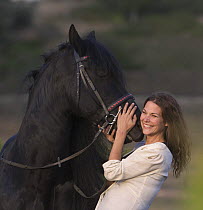 Woman with purebred black Friesian stallion, Ojai, California, USA  Model released