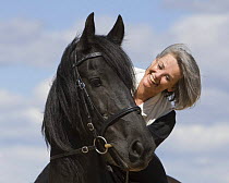 Woman riding purebred black Friesian gelding, USA Model released