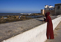 Berber leaning over sea wall in Essaouira, Morocco, November 2008.