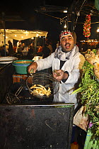 Chef frying food in night souk, Djemaa el-Fna town square, Marrakech, Morocco. November 2008.