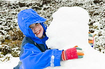 Girl hugging a snowman, Aberdeenshire, Scotland, April Model released