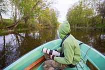 Young boy photographing from a boat on the Suur Emajogi, Palupohja Looduskool, Alam-Pedja nature reserve, Tartumaa, Estonia, May