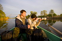 Man and boy photographing from boat on Suur Emajogi, Palupohja Looduskool, Alam-Pedja nature reserve, Tartumaa, Estonia, May