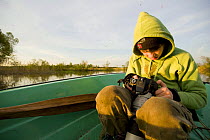 Young boy looking at photos on camera in a boat on the Suur Emajogi River, Palupohja Looduskool, Alam-Pedja nature reserve, Tartumaa, Estonia, May