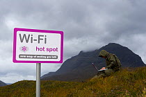 Spoof wi-fi sign with person on a laptop computer, Glen Torridon, Wester Ross, Scotland, October