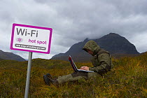 Spoof wi-fi sign with person on a laptop computer, Glen Torridon, Wester Ross, Scotland, October