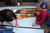 Two women cleaning the wooden boards of their gig "Young Bristol". Underfall Yard, Bristol, March 2009.