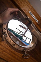 Open porthole aboard Bristol Pilot Cutter "Morwenna", with sign "Do not open at sea". Bristol Floating Harbour, UK. April 2009.