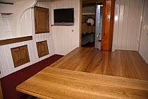 Wooden table and plasma TV in saloon of traditional Bristol Pilot Cutter "Morwenna", Bristol Floating Harbour, UK. April 2009.