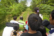 Commuters travelling on a 'skate' - a local form of transport in Manila, Philippines. A motorized platform that can hold up to 30 people and runs on the railway tracks. When the skate meets another he...