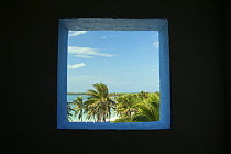 Coconut palm (Cocos nucifera), sea and tropical beach seen through window. Caribbean, Mexico.