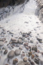 Sea foam and pebbles in a geo (coastal chasm) near Portnahaven, Islay, Scotland.