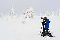 Photographer photographing trees laden with snow and ice (Tykky), Riisitunturi, Finland.