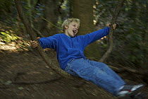 Russell Laman (8 years) playing on a natural vine swing in the rainforest, Lamington National Park, Queensland, Australia. Model released August 2008